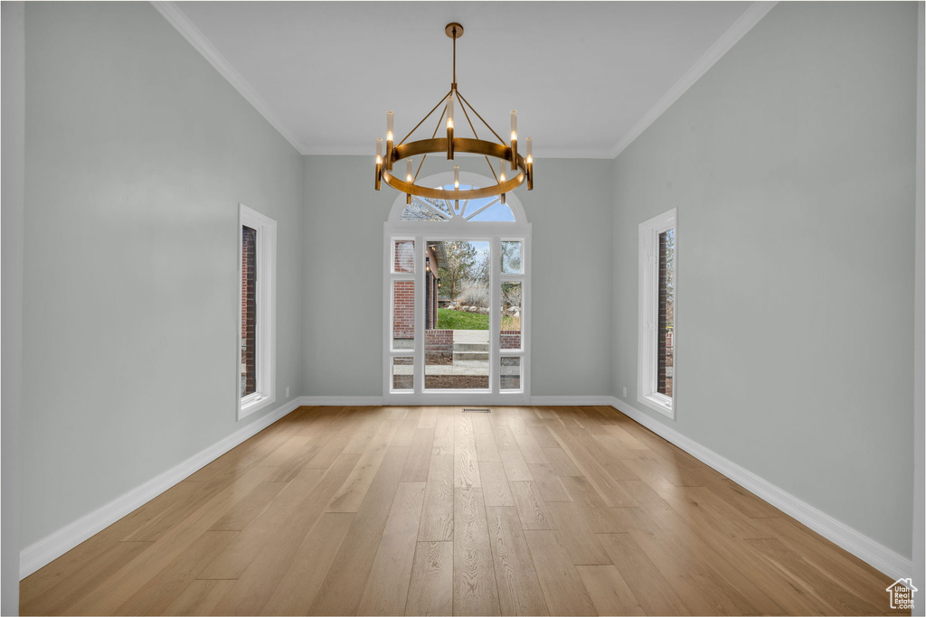 Unfurnished room featuring crown molding, a chandelier, and light hardwood / wood-style flooring