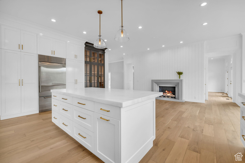 Kitchen with light hardwood / wood-style flooring, stainless steel built in fridge, a center island, and white cabinetry
