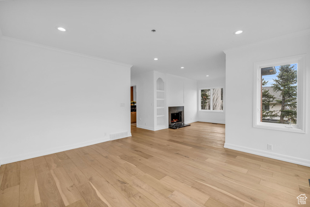 Unfurnished living room with crown molding and light hardwood / wood-style floors