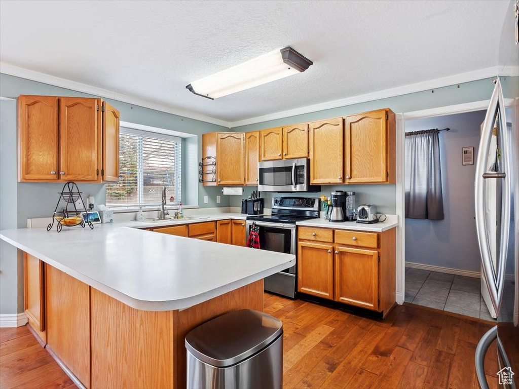 Kitchen featuring sink, stainless steel appliances, tile floors, and kitchen peninsula