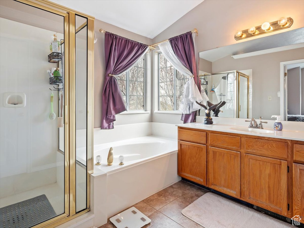 Bathroom featuring tile flooring, vanity, vaulted ceiling, and shower with separate bathtub