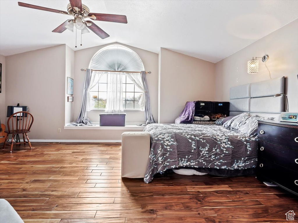 Bedroom with dark hardwood / wood-style flooring, ceiling fan, and lofted ceiling