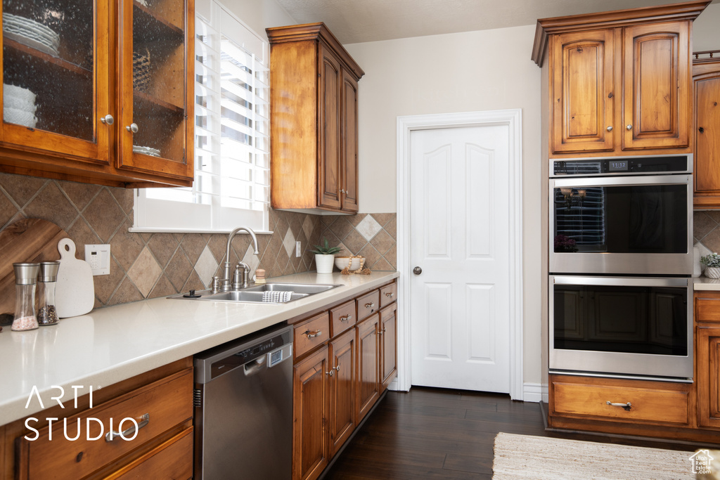 Kitchen featuring appliances with stainless steel finishes, tasteful backsplash, dark hardwood / wood-style floors, and sink