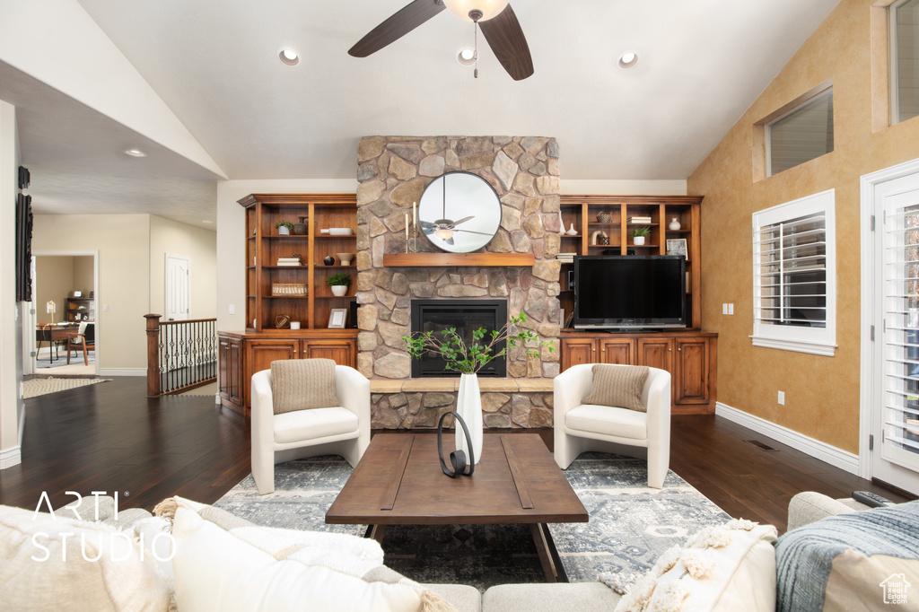 Living room with lofted ceiling, ceiling fan, a stone fireplace, and dark hardwood / wood-style floors