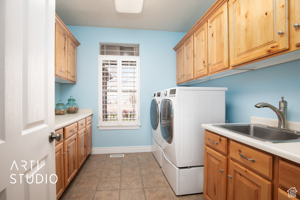 Clothes washing area with sink, independent washer and dryer, cabinets, and light tile floors
