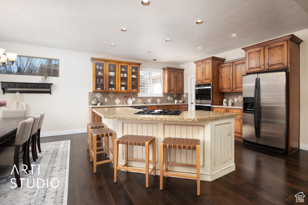 Kitchen featuring dark hardwood / wood-style flooring, a kitchen island, stainless steel appliances, and a kitchen breakfast bar