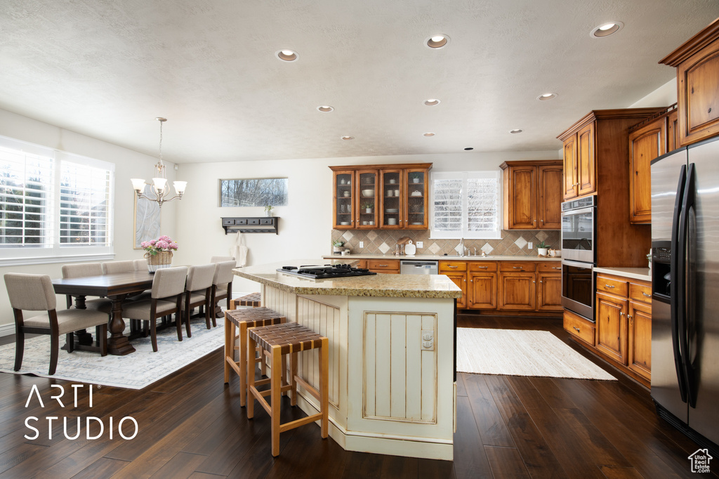 Kitchen featuring a kitchen island, pendant lighting, stainless steel appliances, and plenty of natural light