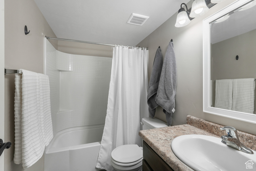 Full bathroom featuring toilet, shower / bathtub combination with curtain, and vanity