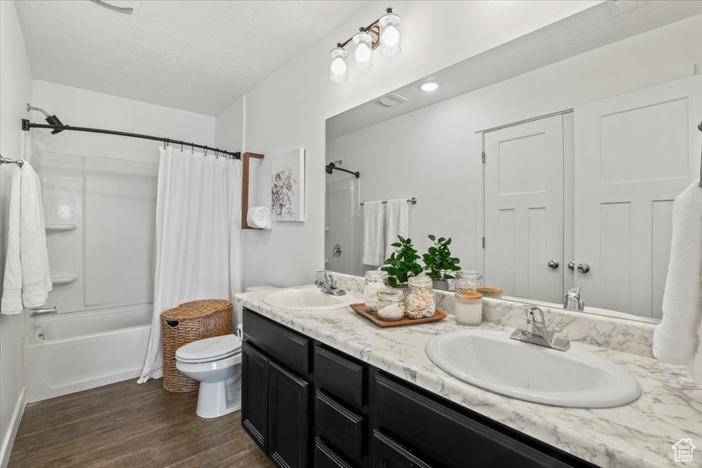 Full bathroom featuring oversized vanity, hardwood / wood-style floors, shower / bath combo with shower curtain, and dual sinks