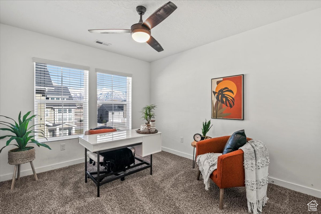 Office area with ceiling fan and dark colored carpet