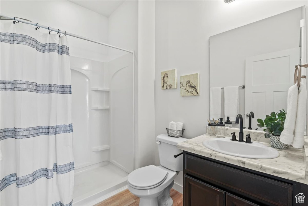 Bathroom with curtained shower, toilet, vanity with extensive cabinet space, and hardwood / wood-style flooring