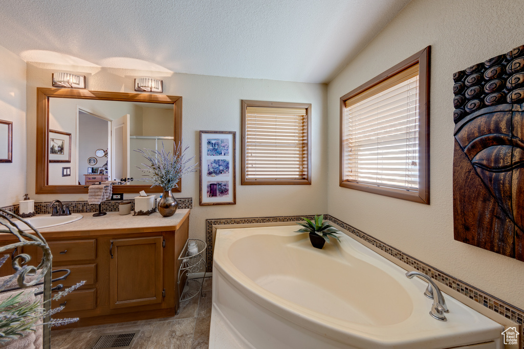 Bathroom featuring tile flooring, a textured ceiling, large vanity, and a bathtub