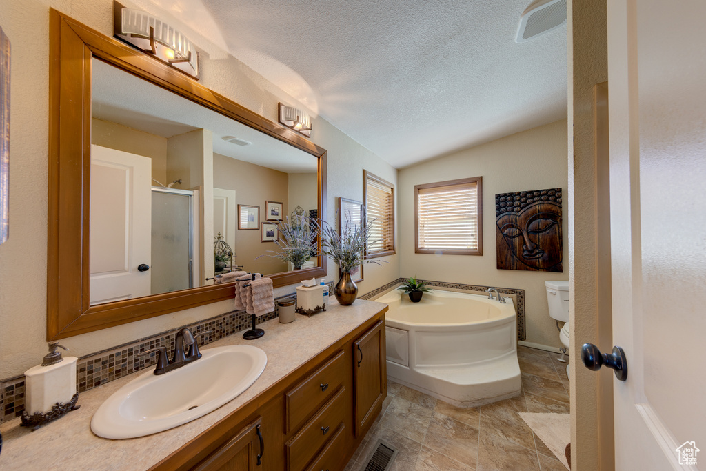 Full bathroom with large vanity, tile flooring, vaulted ceiling, toilet, and a textured ceiling