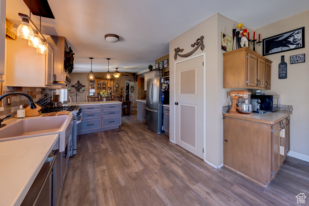 Kitchen featuring ceiling fan, backsplash, dark hardwood / wood-style flooring, stainless steel appliances, and pendant lighting