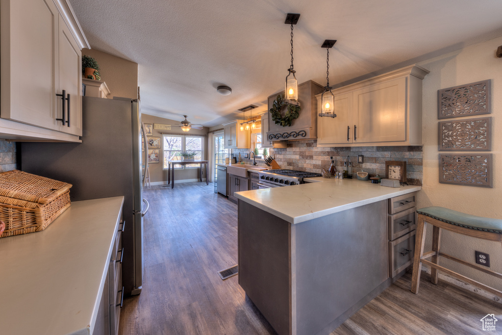 Kitchen with hanging light fixtures, dark hardwood / wood-style floors, kitchen peninsula, and a breakfast bar