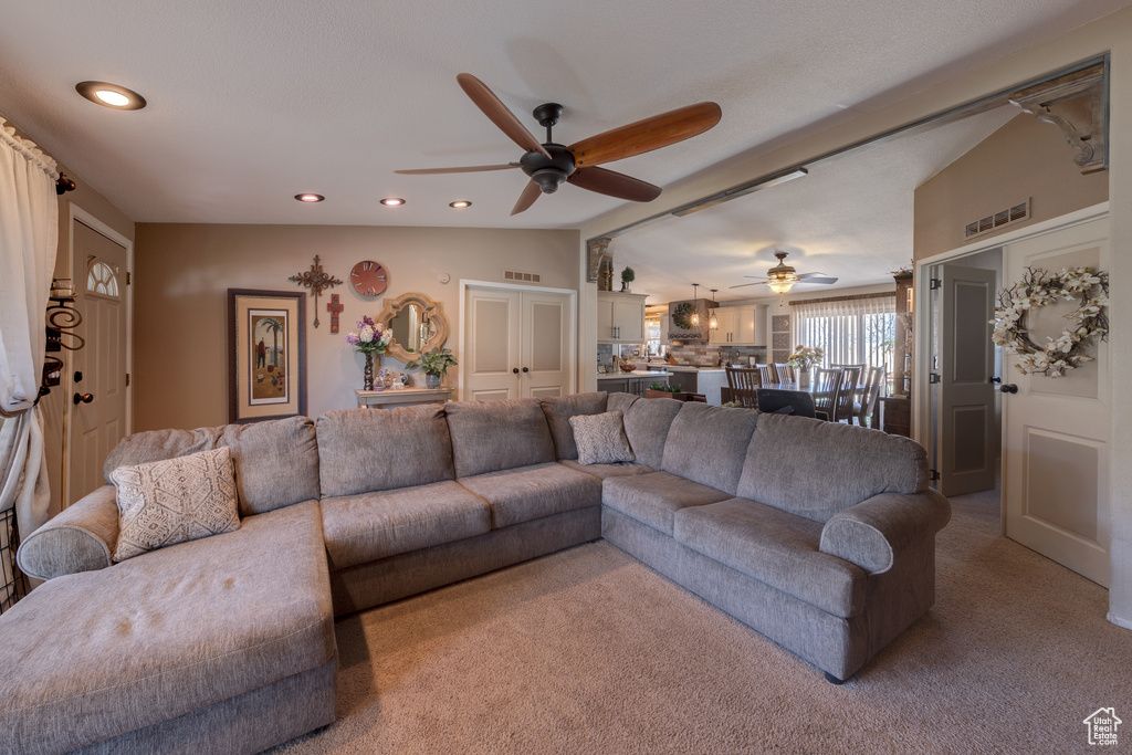 Living room with light colored carpet, lofted ceiling, and ceiling fan