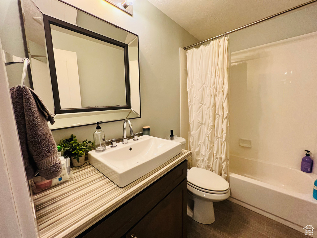 Full bathroom with shower / bathtub combination with curtain, toilet, and vanity with extensive cabinet space