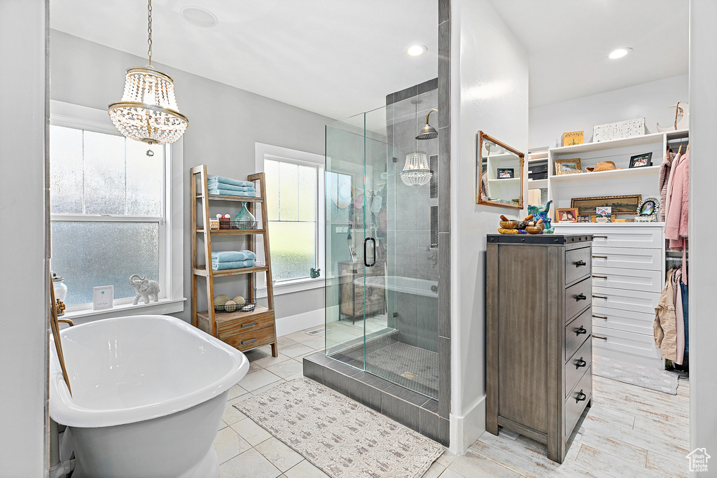 Bathroom with oversized vanity, shower with separate bathtub, a chandelier, and tile flooring
