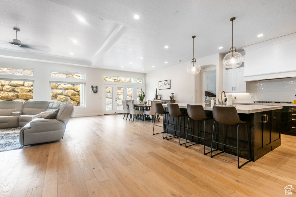 Kitchen featuring light hardwood / wood-style flooring, backsplash, a breakfast bar area, and a center island with sink
