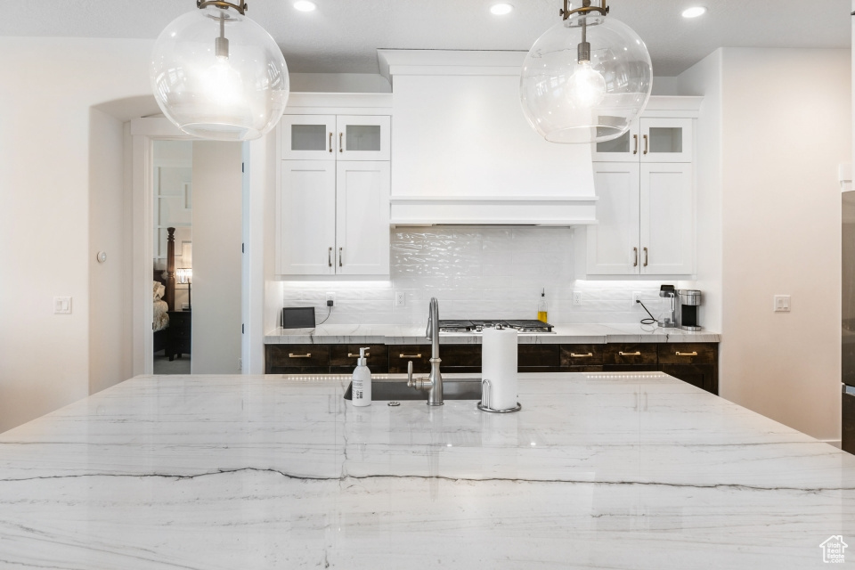 Kitchen featuring tasteful backsplash, decorative light fixtures, and white cabinetry