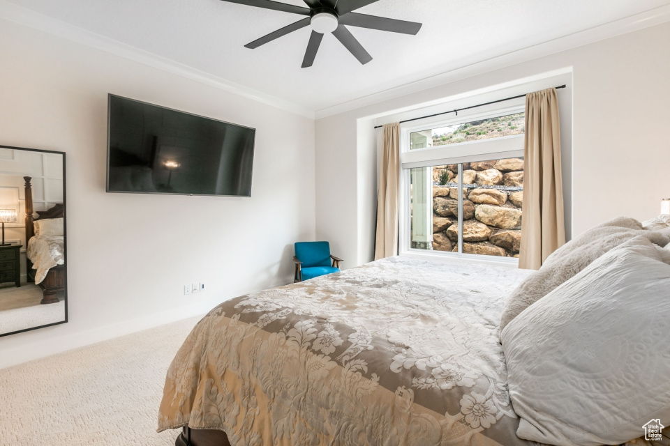 Carpeted bedroom featuring ornamental molding and ceiling fan