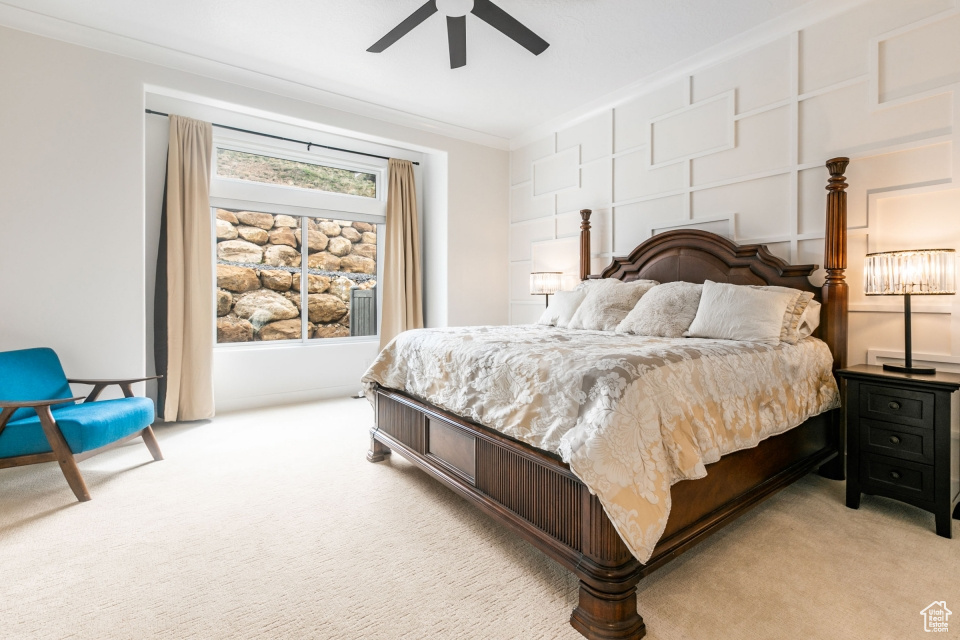 Bedroom with ceiling fan, crown molding, and light colored carpet