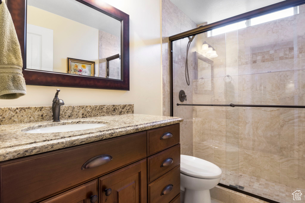 Bathroom featuring toilet, large vanity, and walk in shower