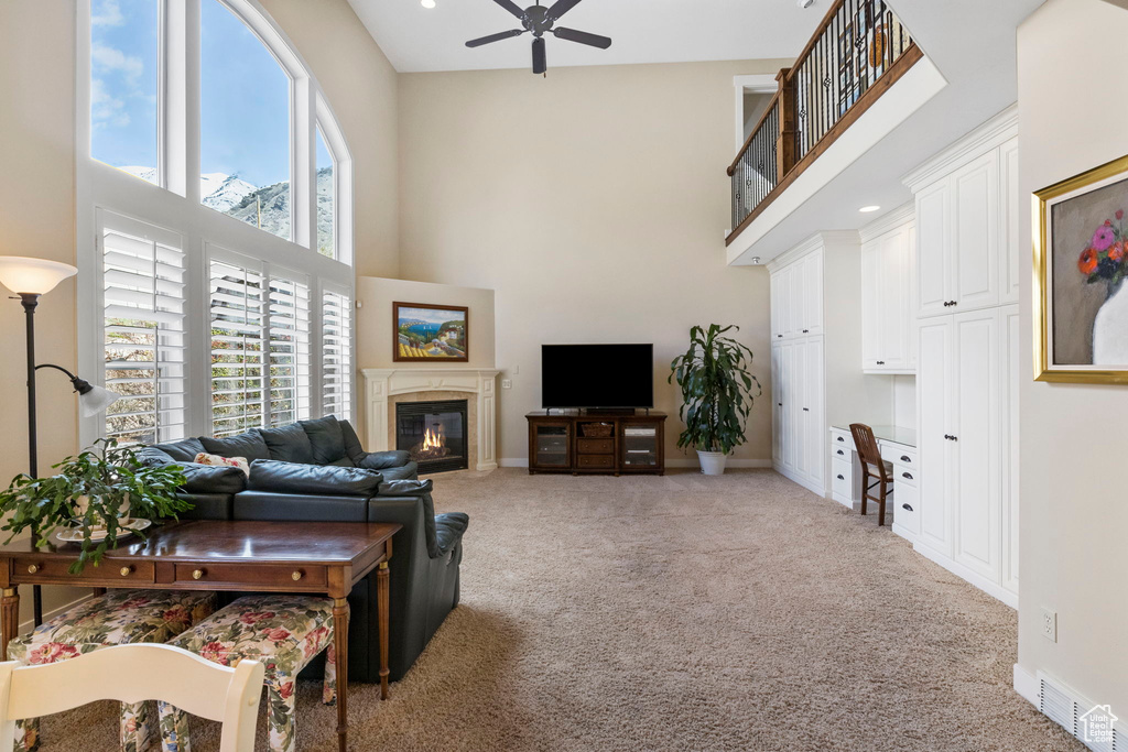 Carpeted living room with ceiling fan and a towering ceiling