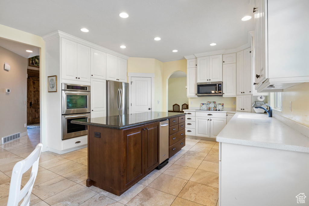 Kitchen with a center island, stainless steel appliances, and white cabinetry