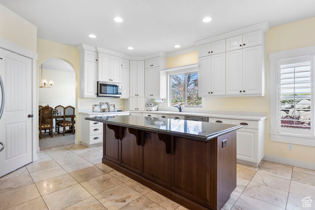 Kitchen with white cabinets, a breakfast bar area, a center island, and light tile floors