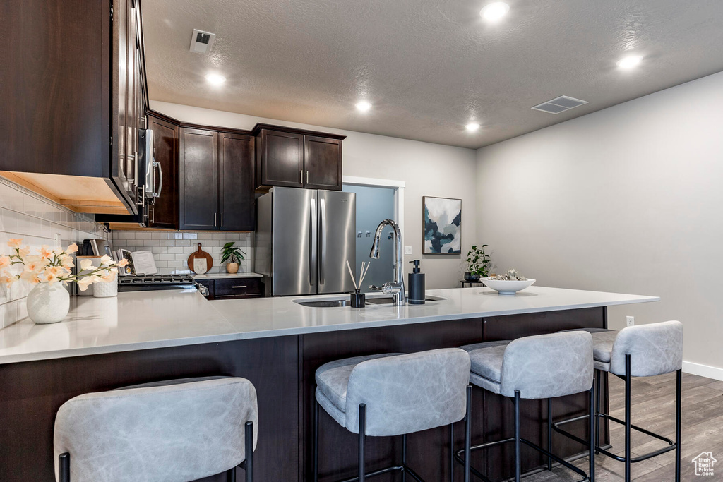 Kitchen with tasteful backsplash, dark hardwood / wood-style floors, gas range, stainless steel fridge, and sink