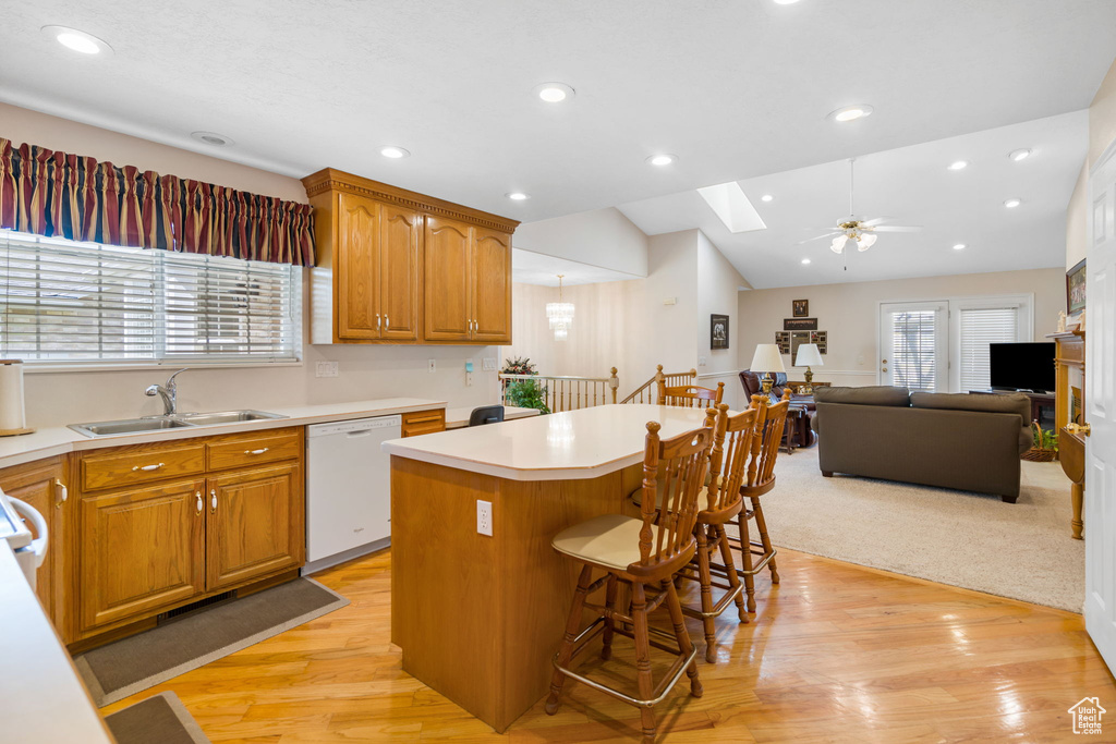 Kitchen featuring a center island, ceiling fan, white dishwasher, a breakfast bar area, and light wood-type flooring