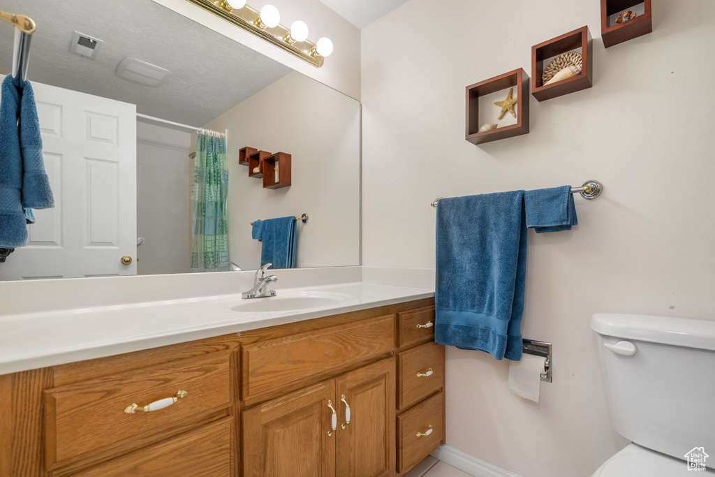 Bathroom with a textured ceiling, toilet, and large vanity