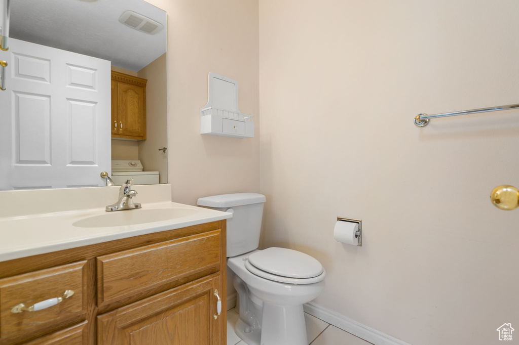 Bathroom featuring washer / clothes dryer, tile flooring, toilet, and large vanity