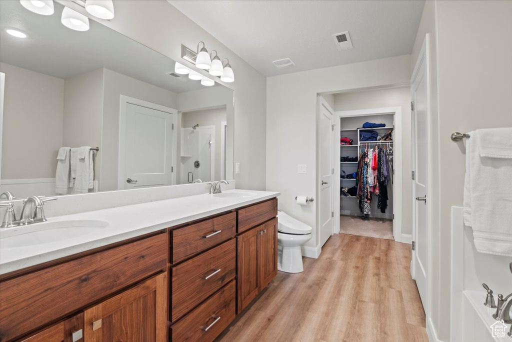 Bathroom with dual vanity, toilet, and wood-type flooring