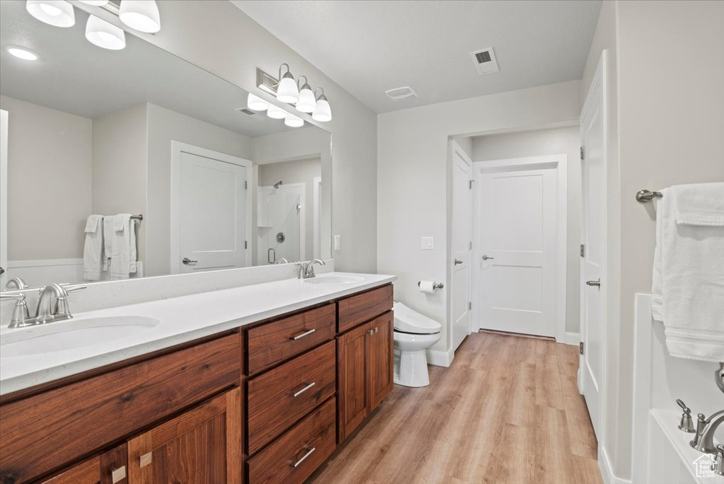 Bathroom featuring toilet, double vanity, and wood-type flooring