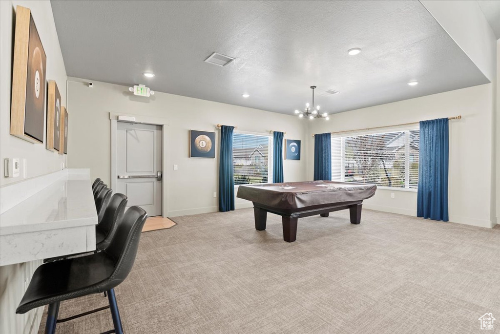 Playroom featuring a notable chandelier, light colored carpet, pool table, and a healthy amount of sunlight