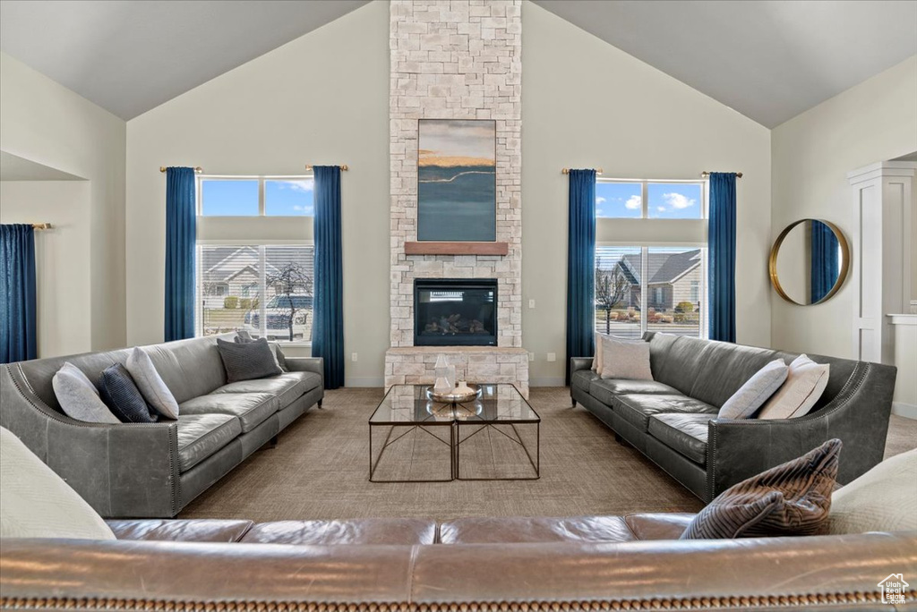 Living room with a stone fireplace, plenty of natural light, and high vaulted ceiling