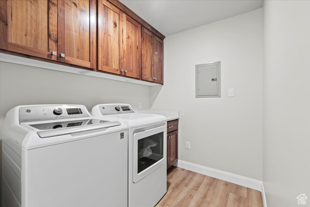 Laundry room featuring cabinets, washer and clothes dryer, and light hardwood / wood-style floors