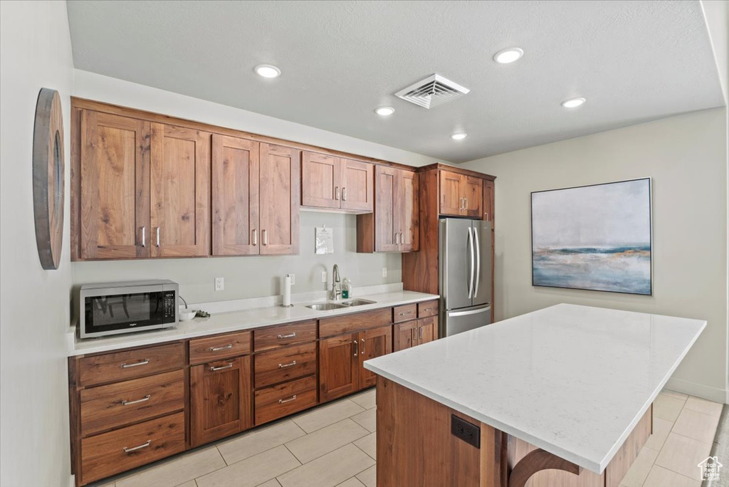 Kitchen featuring light tile flooring, sink, stainless steel appliances, and a center island