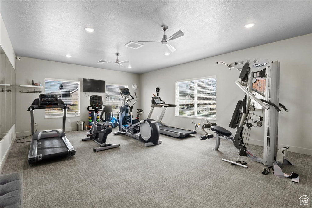 Exercise room with ceiling fan, a textured ceiling, and carpet floors