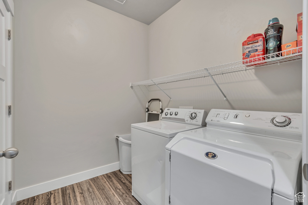 Clothes washing area featuring separate washer and dryer and wood-type flooring