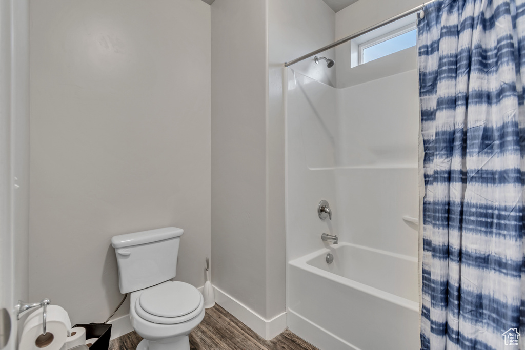 Bathroom with shower / bath combination with curtain, toilet, and hardwood / wood-style floors