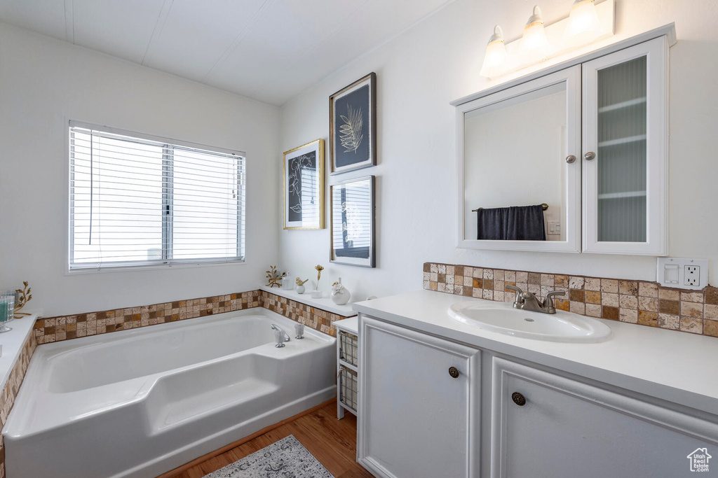 Bathroom featuring a bathing tub, oversized vanity, and wood-type flooring