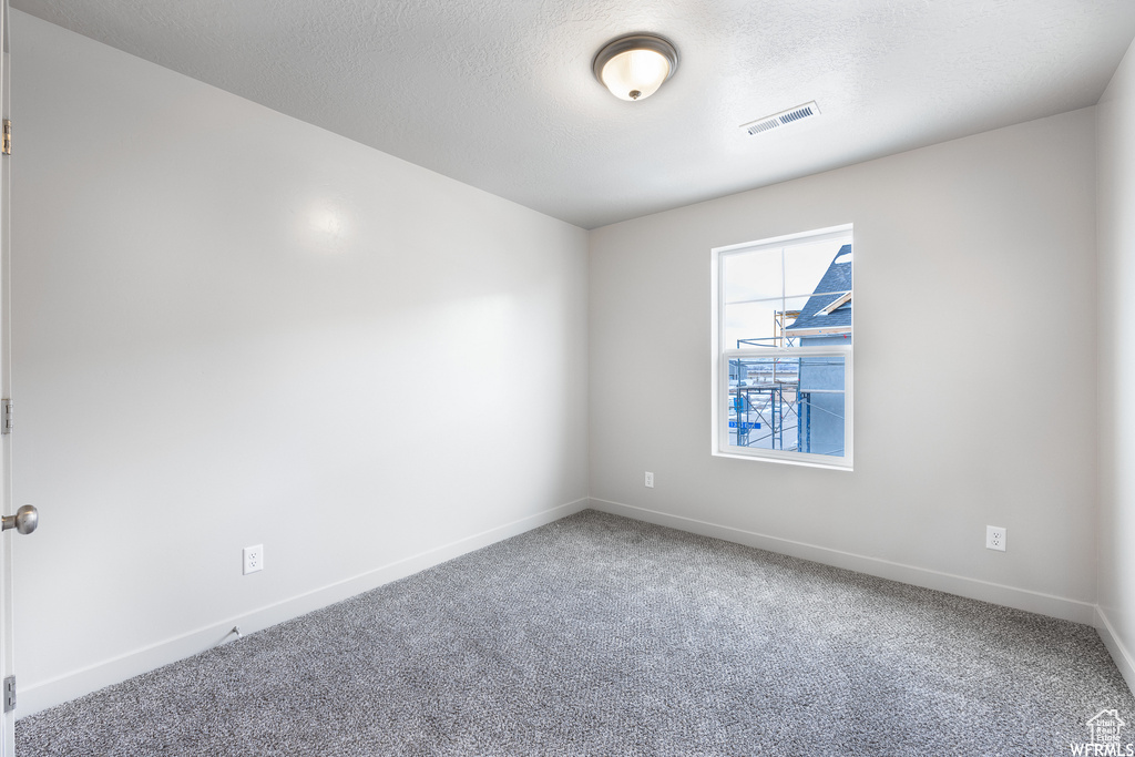 Carpeted empty room with a textured ceiling