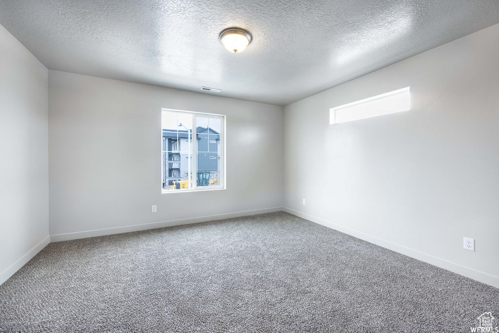 Spare room featuring a textured ceiling and carpet floors