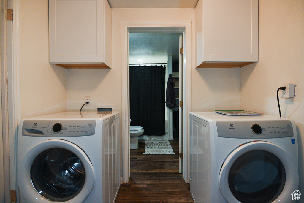 Laundry area featuring dark wood-type flooring, cabinets, and washing machine and dryer