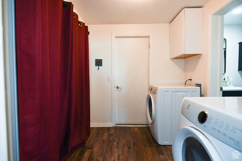 Washroom featuring washer hookup, washing machine and dryer, cabinets, and dark wood-type flooring
