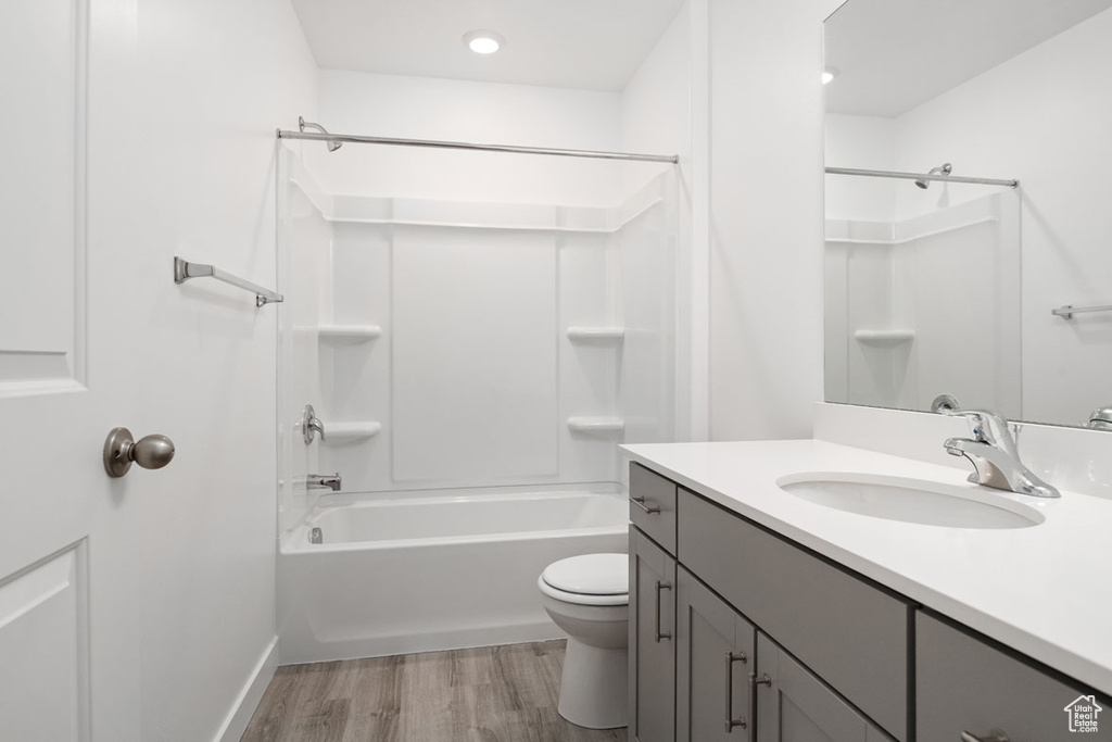 Full bathroom with vanity, toilet, hardwood / wood-style floors, and shower / bathing tub combination