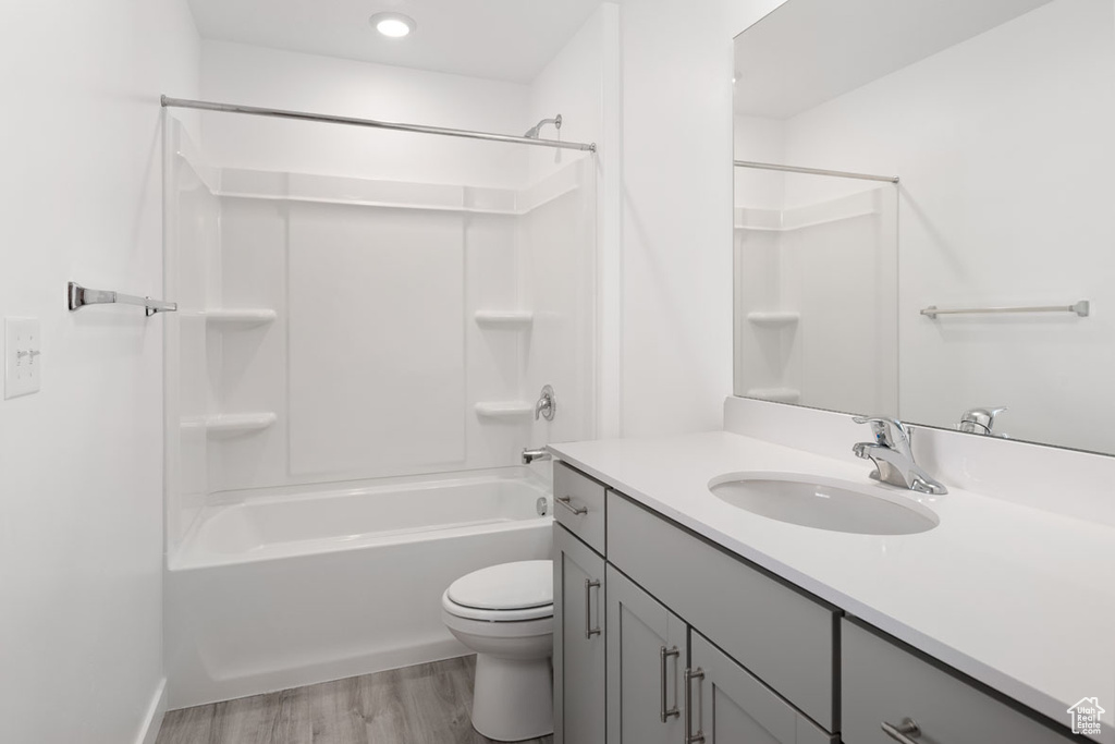 Full bathroom with toilet, wood-type flooring, vanity with extensive cabinet space, and shower / bathtub combination